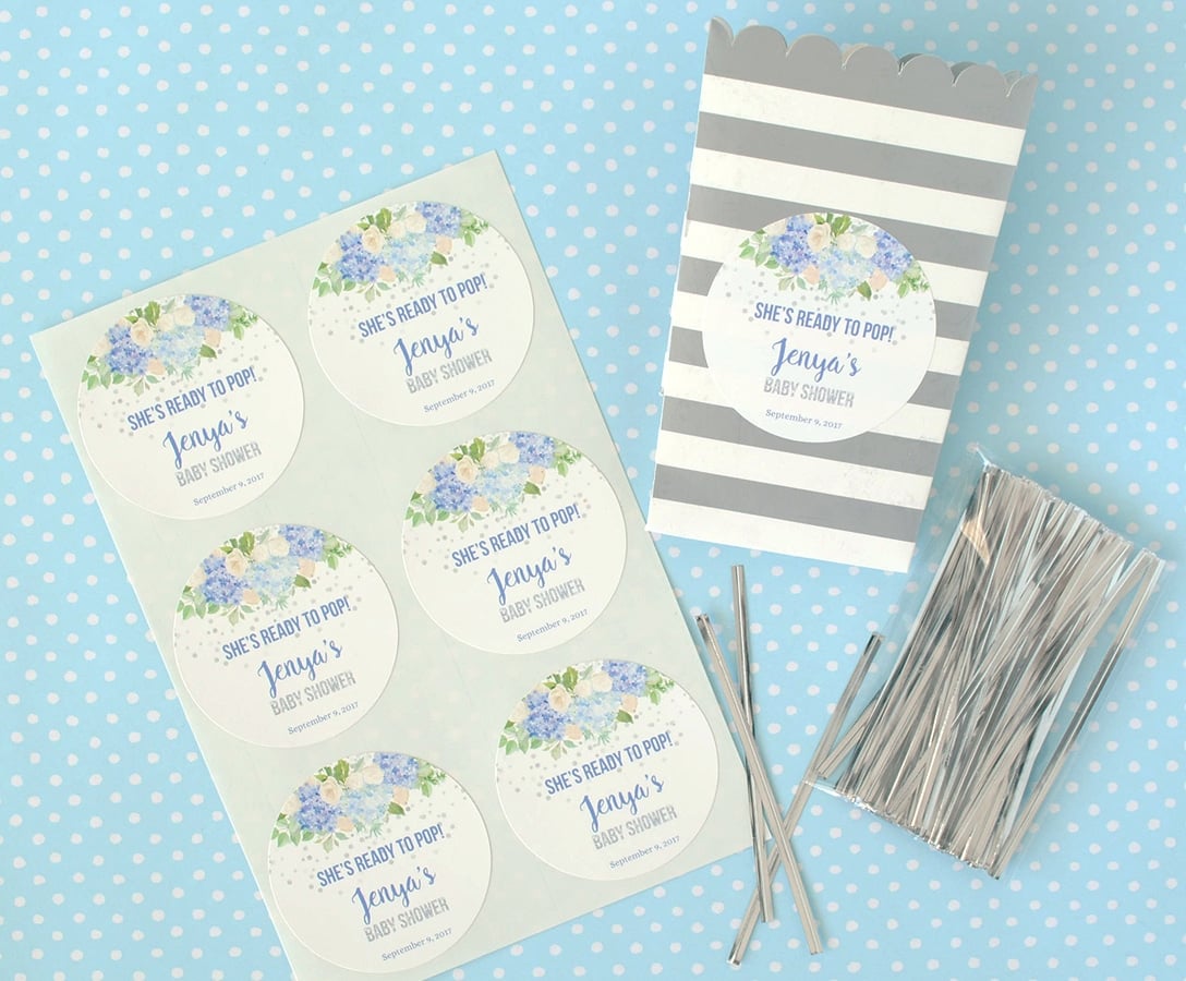 Materials to make a baby boy shower favor filled with kettle corn and finished with a custom baby shower sticker.