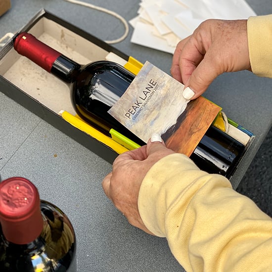 Turn a shoe box into a wine label jig. It holds the bottle securely so you can add your custom label.