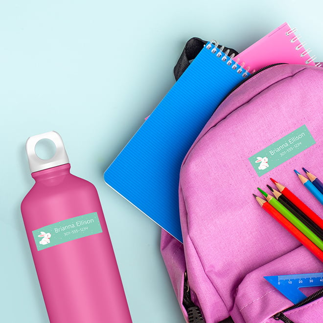 Kids name stickers on a kids thermos and backpack. Make your own name stickers with your child's name. Kids name sticker with a white bunny and teal background.
